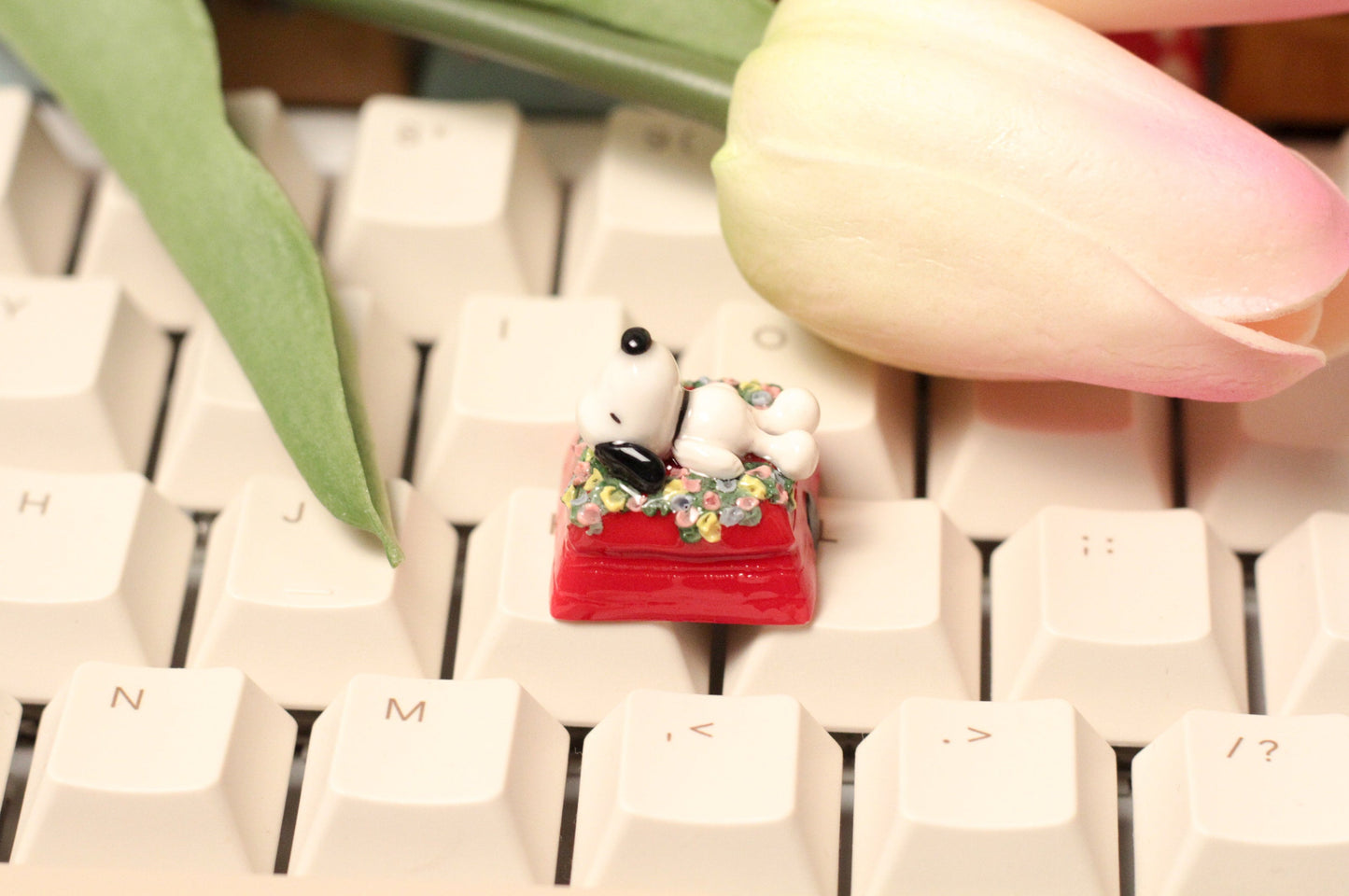 Classic Snoopy sleeping on top of his iconic red dog house on a bed of flowers.