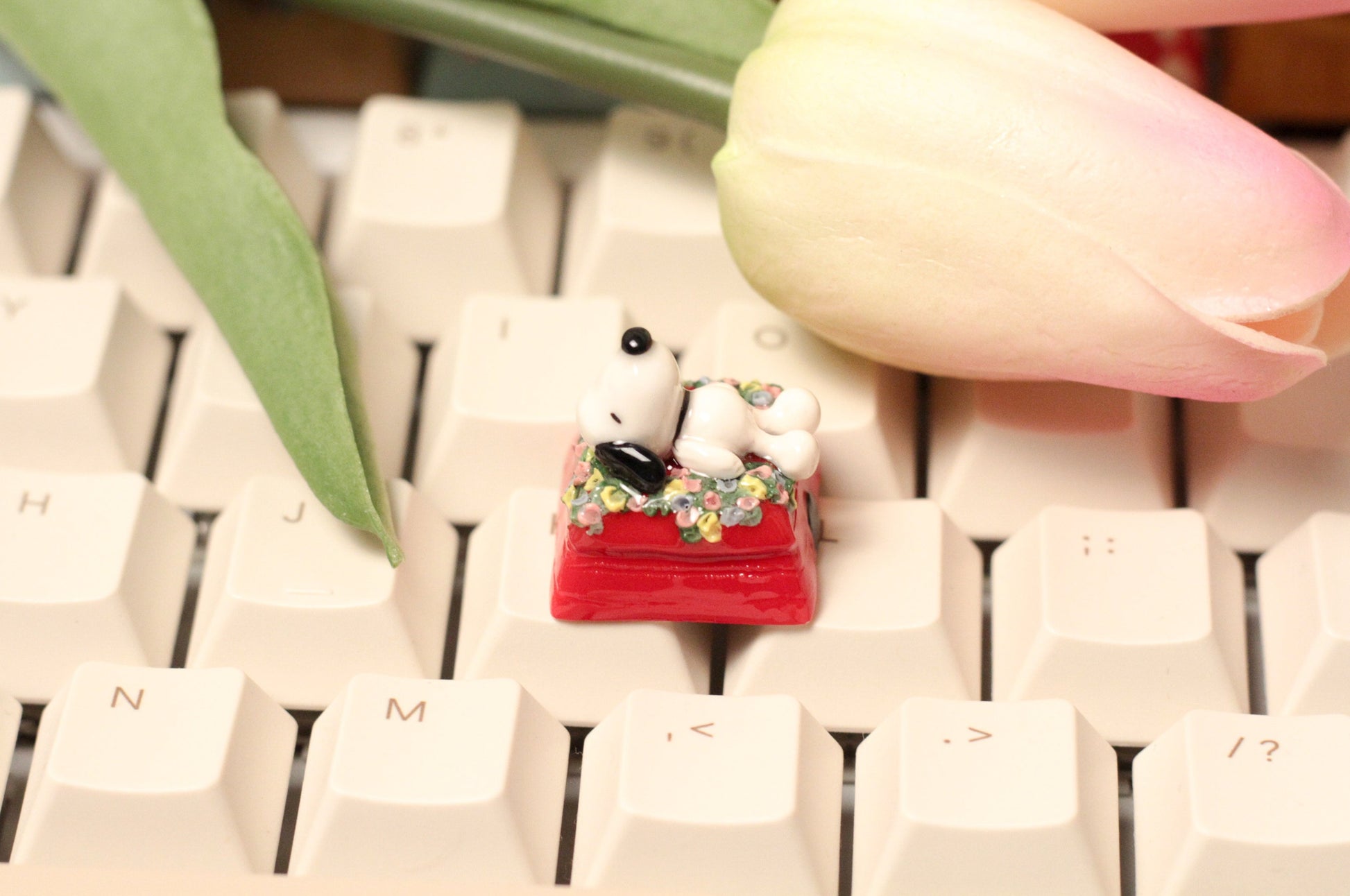 Classic Snoopy sleeping on top of his iconic red dog house on a bed of flowers.