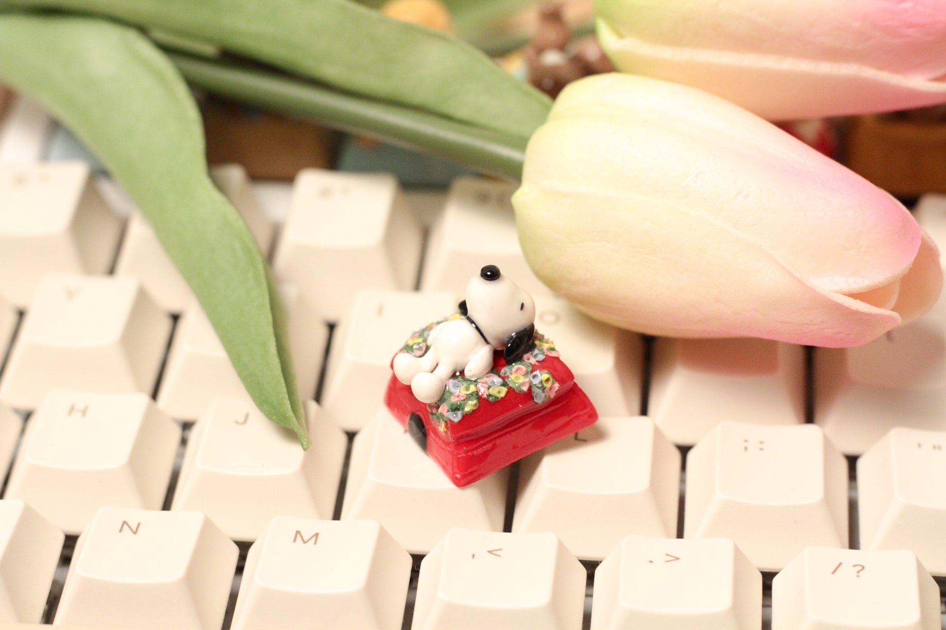 Classic Snoopy sleeping on top of his iconic red dog house on a bed of flowers.