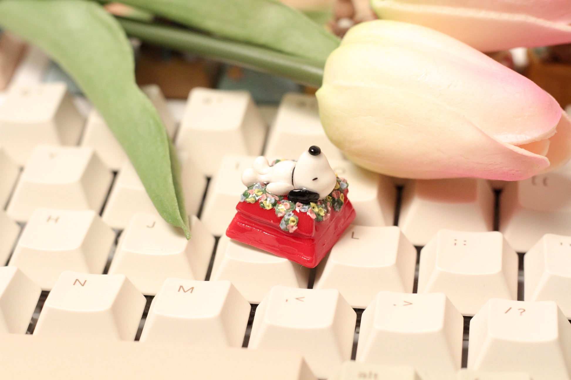 Classic Snoopy sleeping on top of his iconic red dog house on a bed of flowers.