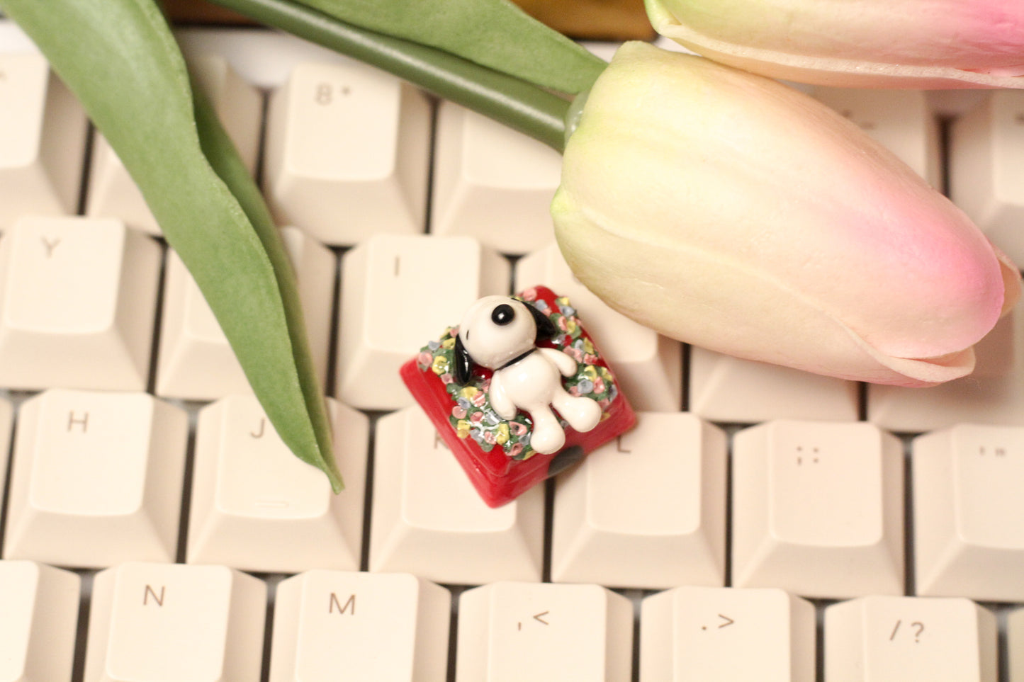 Classic Snoopy sleeping on top of his iconic red dog house on a bed of flowers.